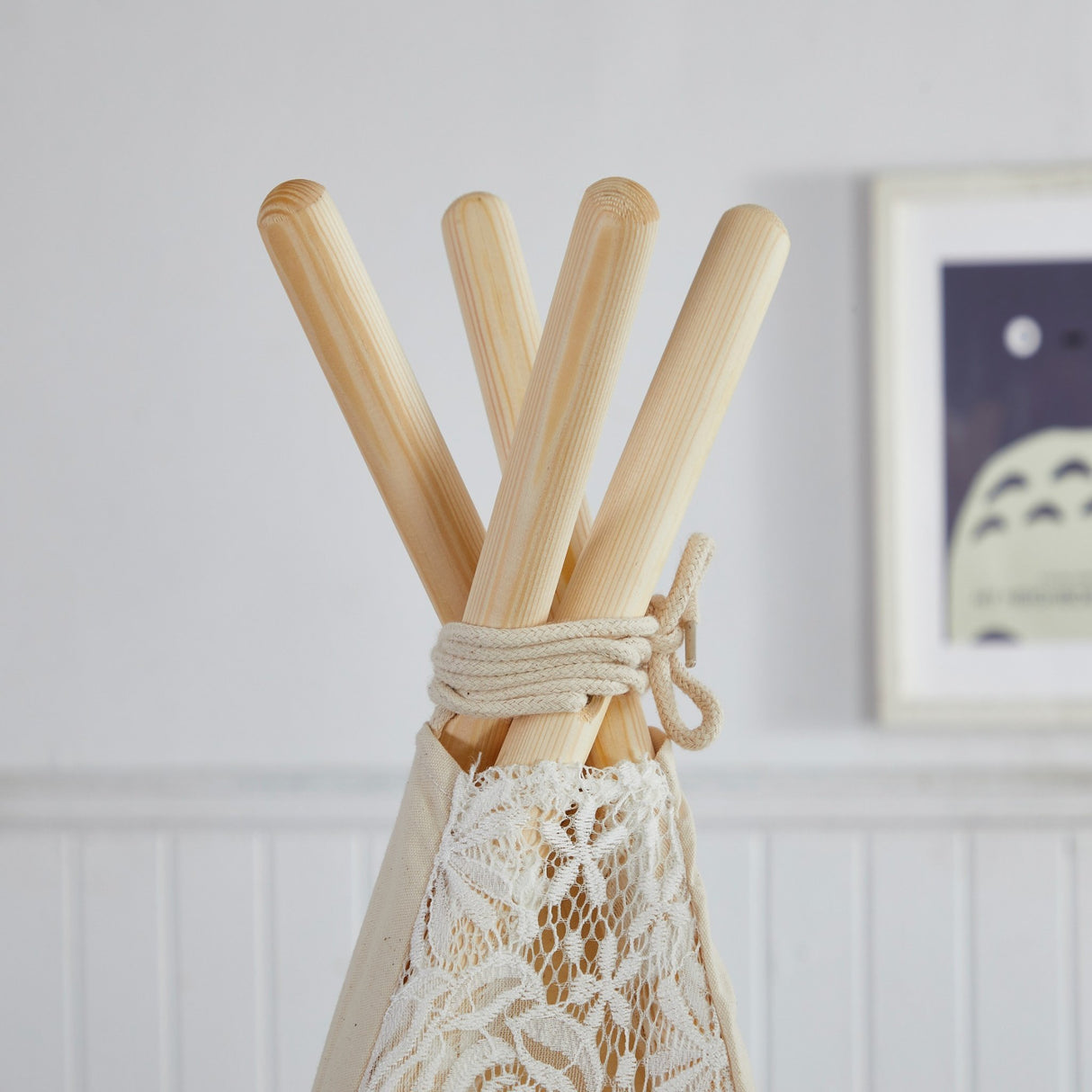 Wooden sticks tied together with a lace ribbon against a white wall.